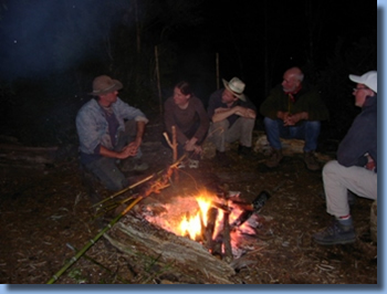 Gr4oup of people sitting around a fire on a horseback trailride in chilean andes